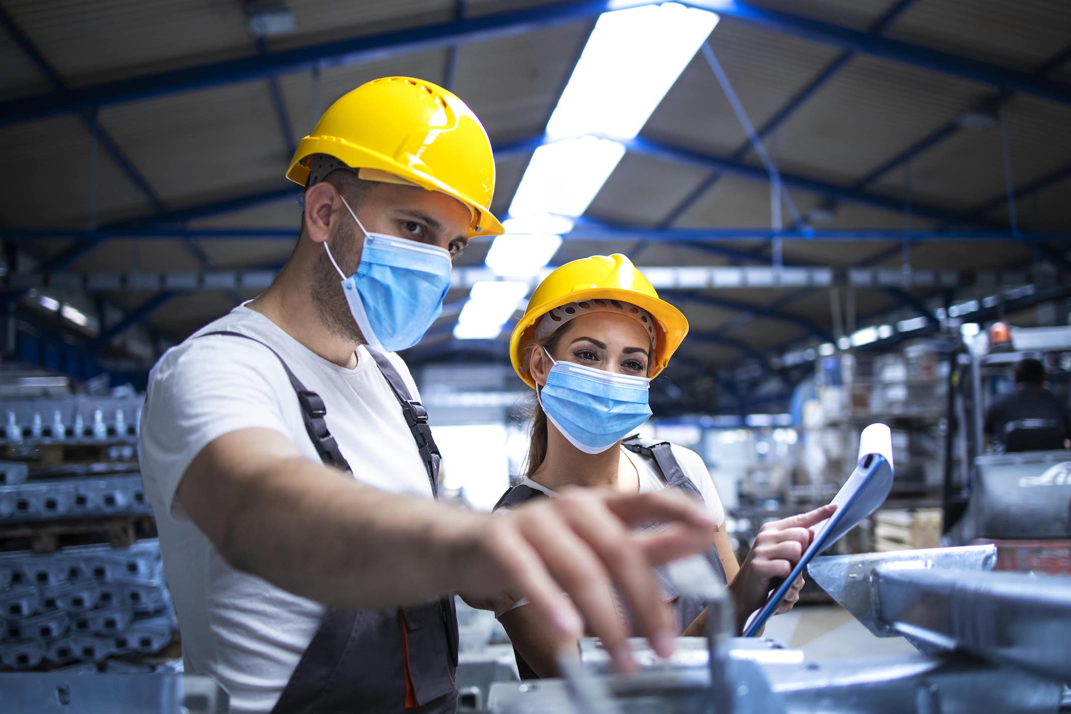 industrial-workers-with-face-masks-protected-against-corona-virus-discussing-about-metal-parts-factory-min